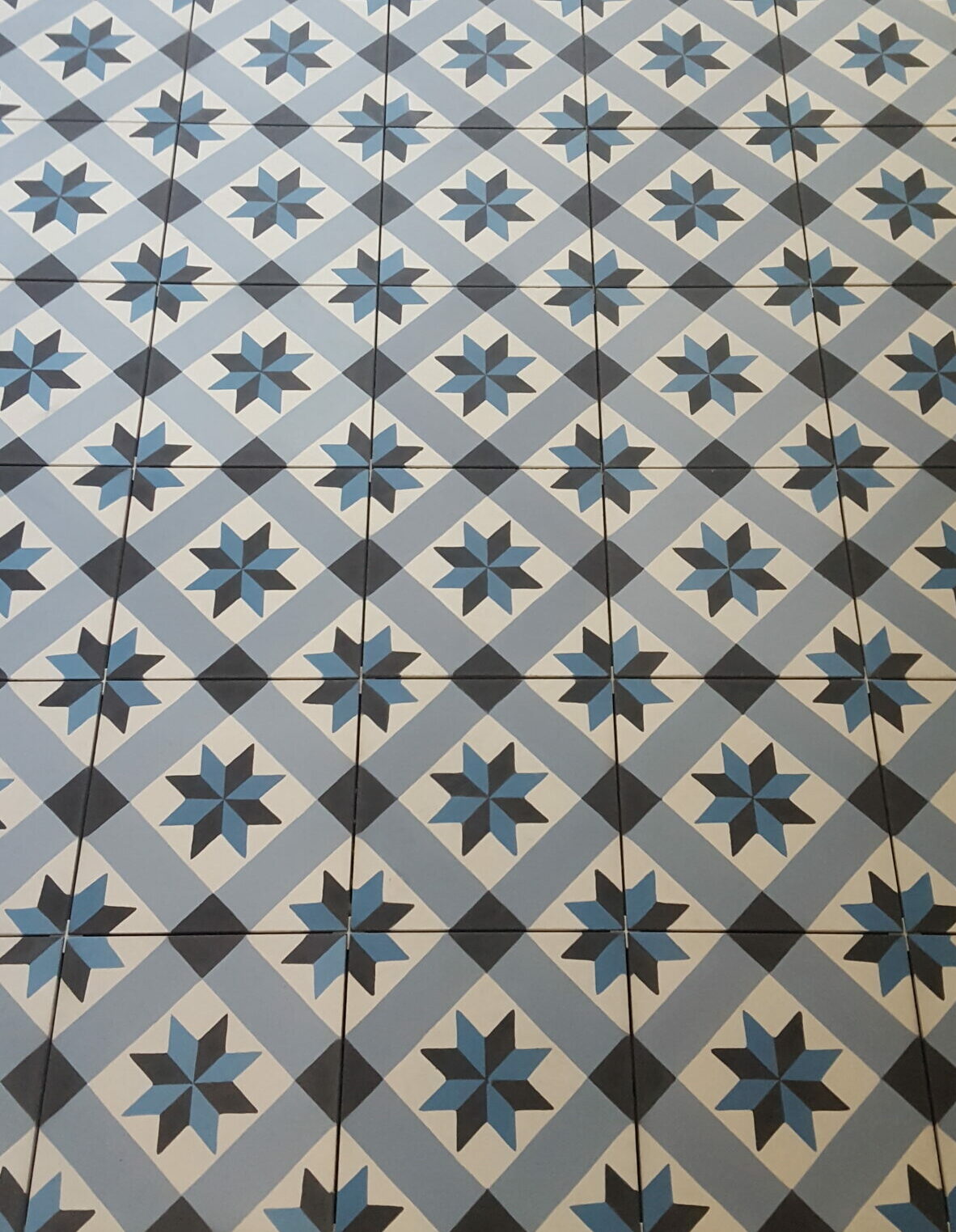 Pose de carrelage Sol en carreaux de ciment à motifs géométriques bleus et noirs sur fond blanc à Lyon