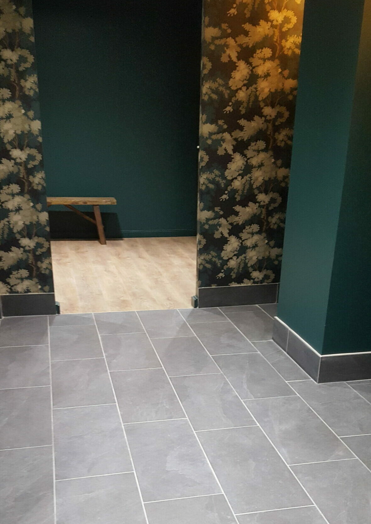 Pose de carrelage Espace intérieur avec sol en carrelage gris, murs vert foncé et papier peint floral doré à Lyon