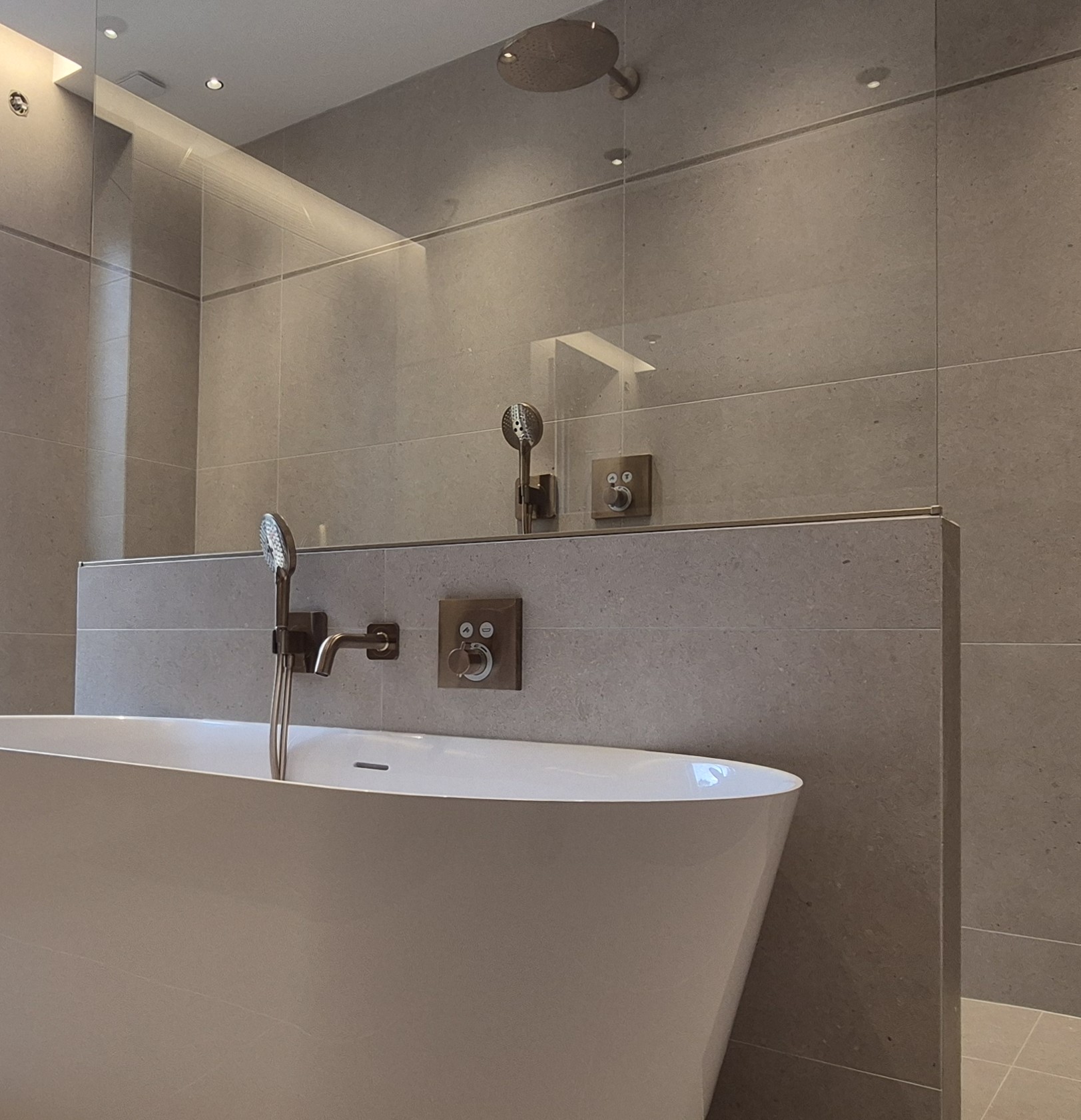 Pose de carrelage Salle de bains moderne avec baignoire îlot, carrelage effet pierre et robinetterie murale finition aluminium brossé à Lyon