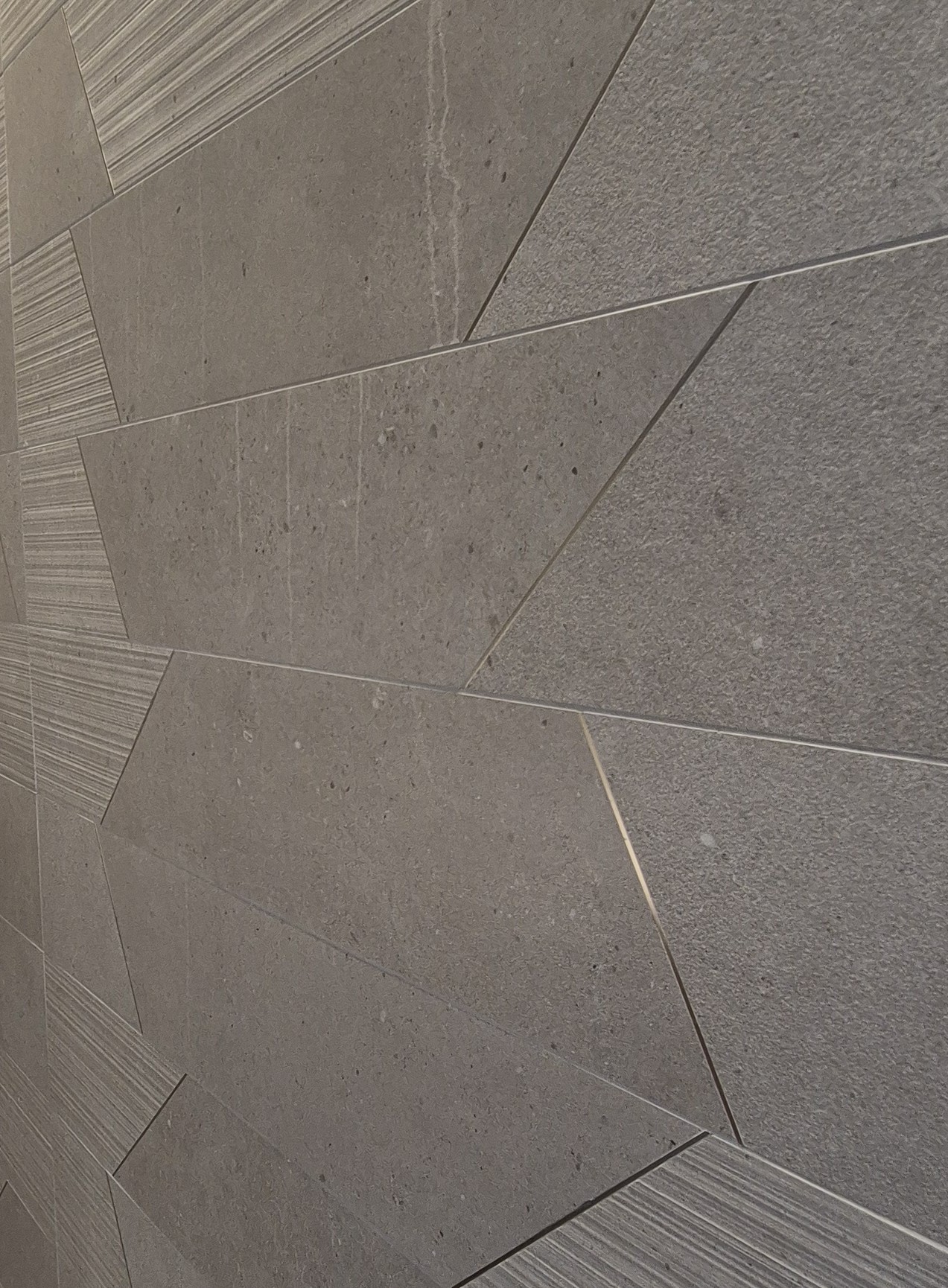 Pose de carrelage Mur en carrelage effet pierre gris foncé avec un design géométrique et finitions texturées à Lyon