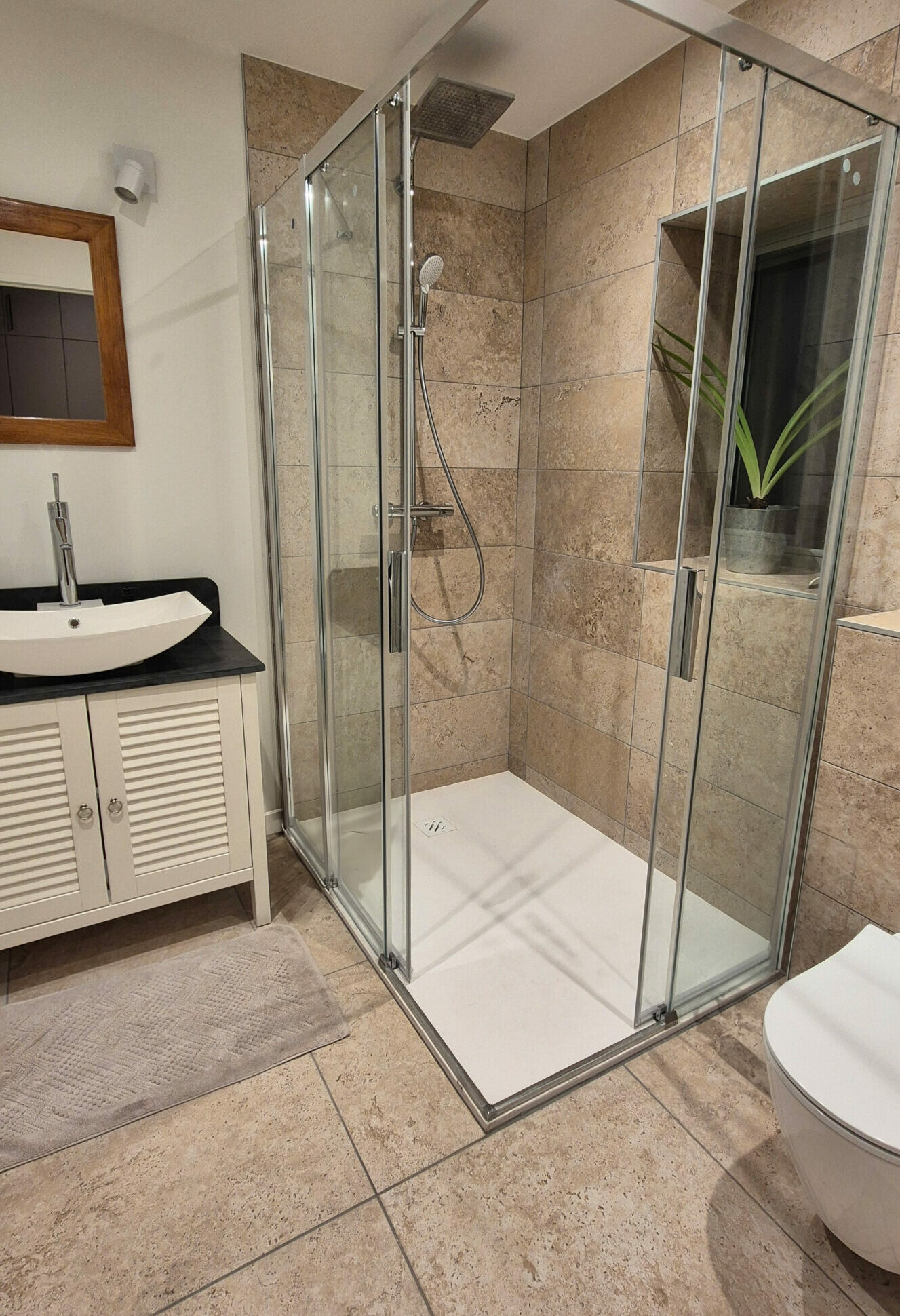 Pose de carrelage Salle de bains avec douche à l’italienne, carrelage effet pierre beige et meuble vasque en bois blanc à Lyon