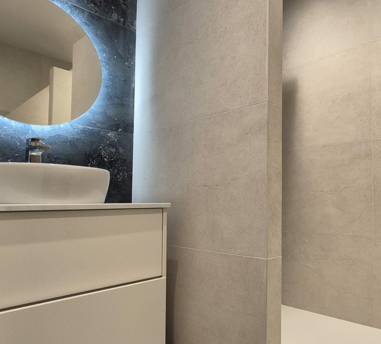 Pose de carrelage Salle de bains moderne effet pierre beige et miroir rétroéclairé sur mur en marbre noir à Lyon