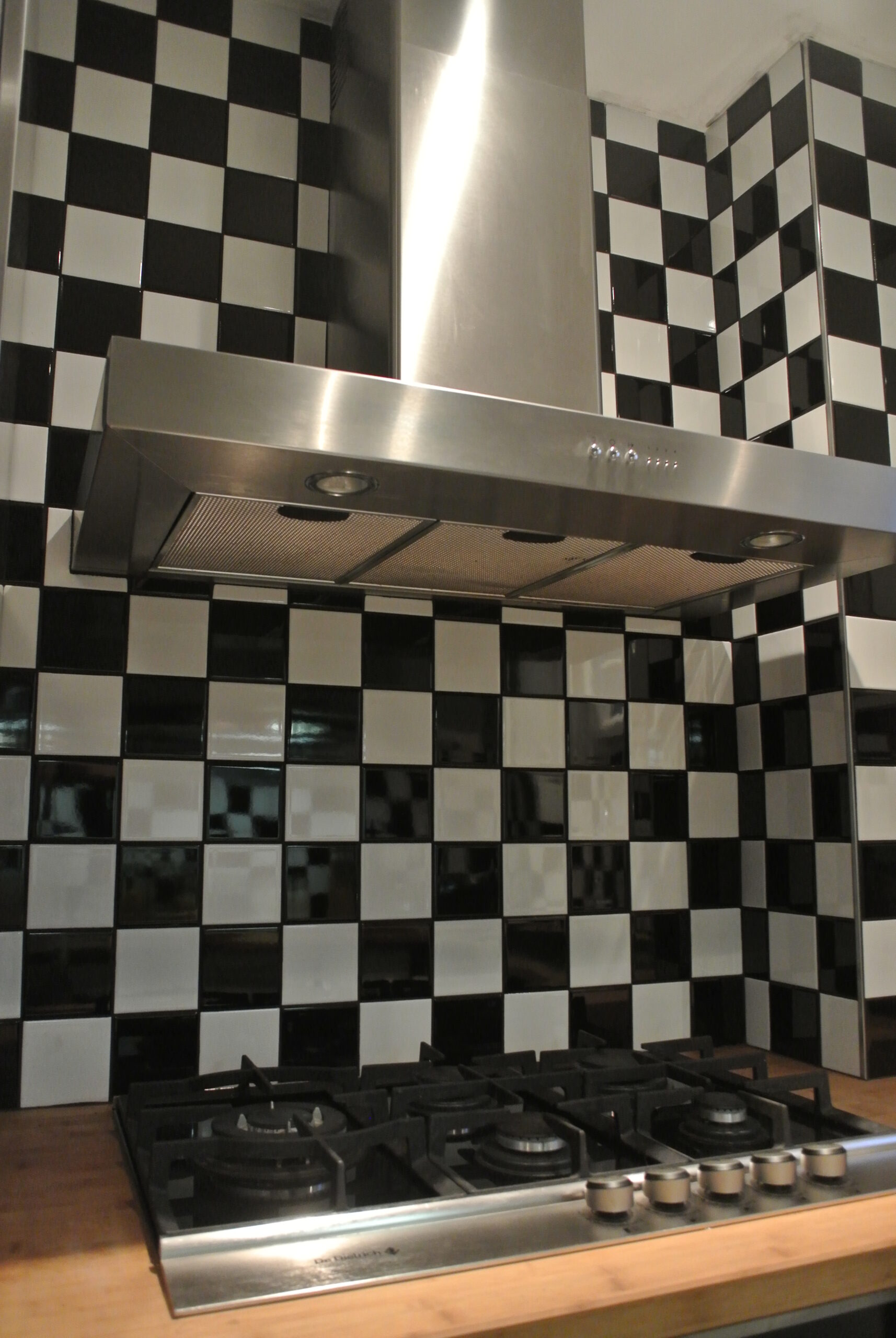 Pose de carrelage Cuisine avec hotte en inox et crédence en carrelage damier noir et blanc à Lyon